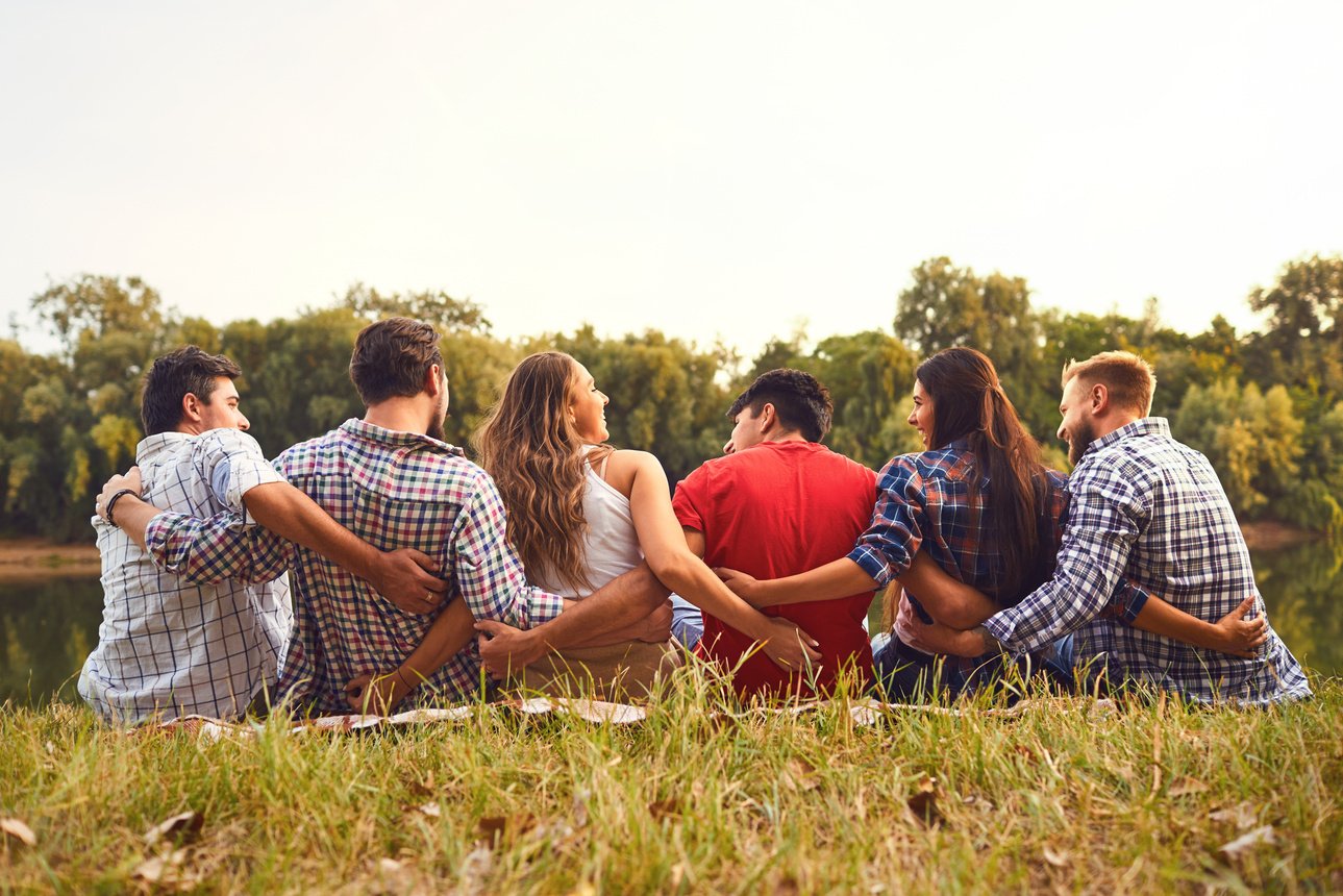 Young People Sit on the Grass Hugging in Nature in the Park